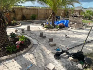 Active paver patio installation with stone pavers around palm trees, showcasing paver patios and driveways in Summerdale, AL.