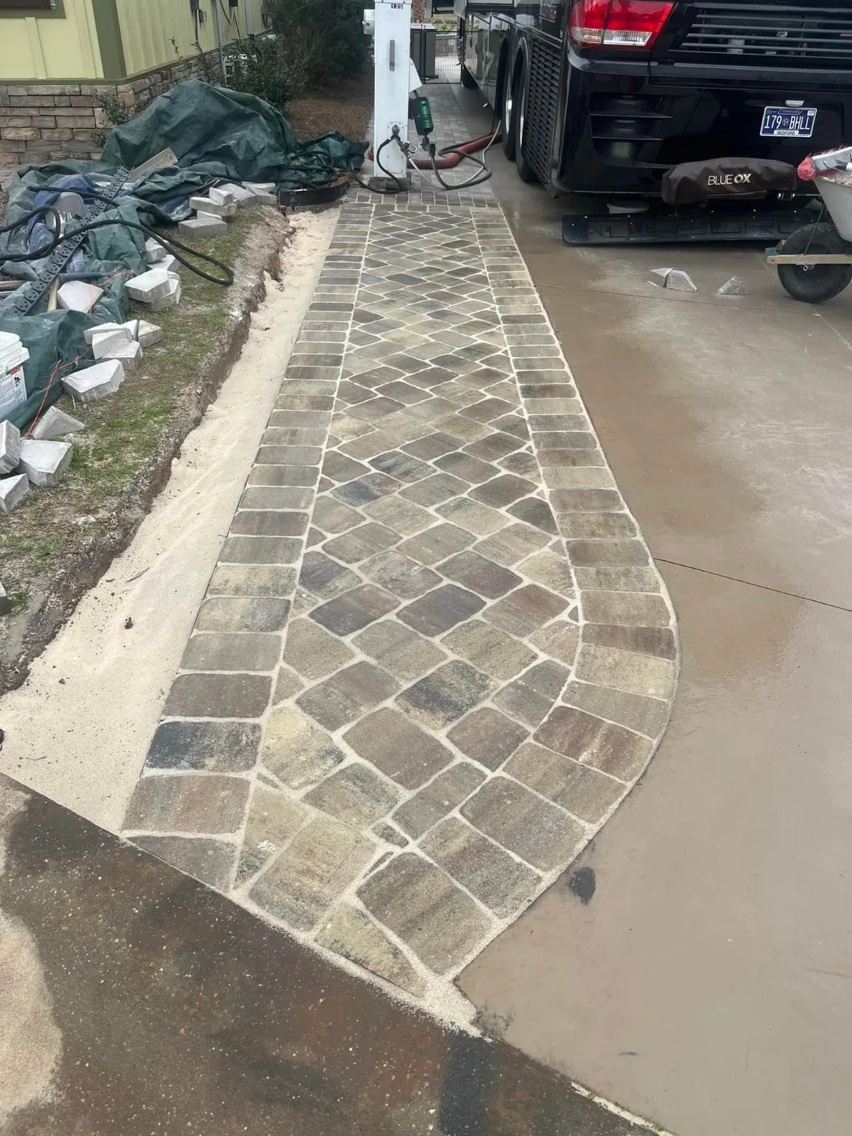 A stone walkway being finished next to an RV driveway pad, ideal for paver patios and driveways in Summerdale, AL.